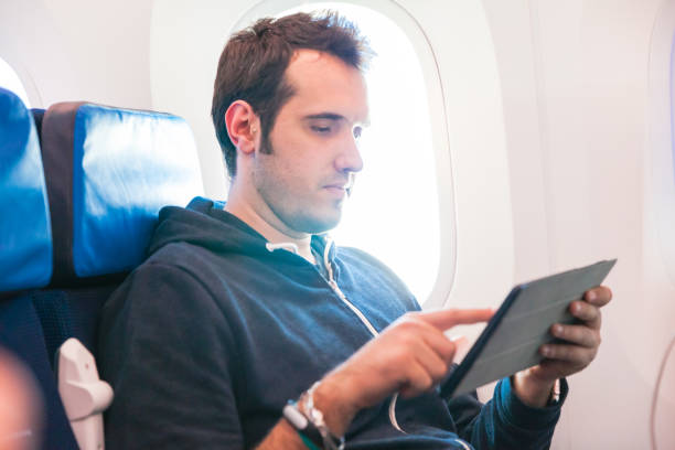 istock Man sitting on an airplane holding digital tablet 666037194
