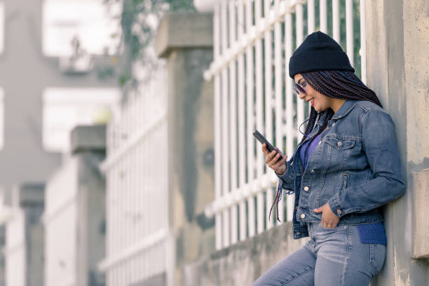 istock Woman use phone in front of wall building 666043742