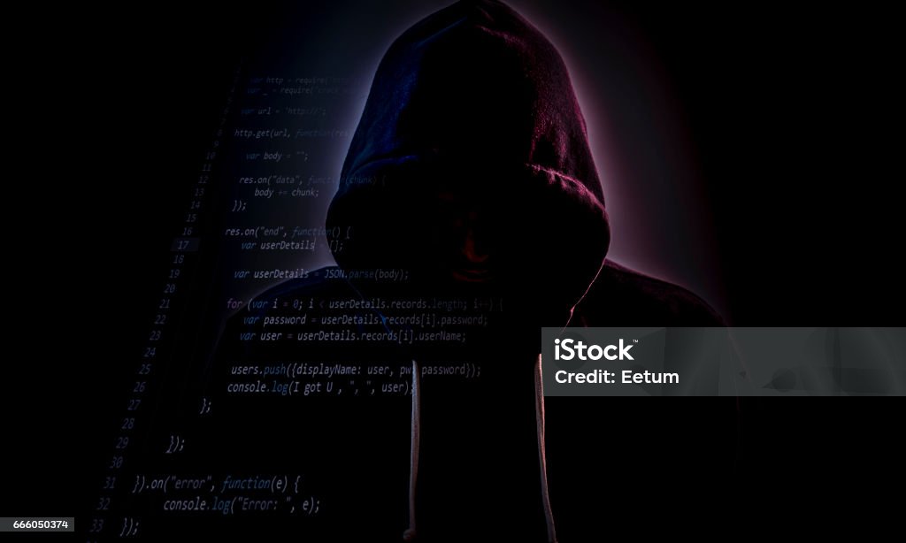 Hooded hacker in dark with code Malicious figure in hood lurking in the dark with some code layer Hooded Shirt Stock Photo