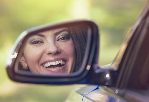 魅力的な若い女性は鏡の中の彼女の車の反射を運転 - owner women car rear view mirror ストックフォトと画像