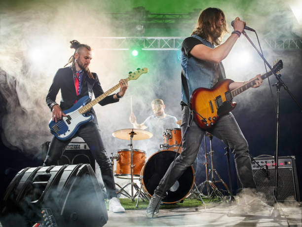rock band performs on stage. guitarist, bass guitar and drums. - bass drum imagens e fotografias de stock