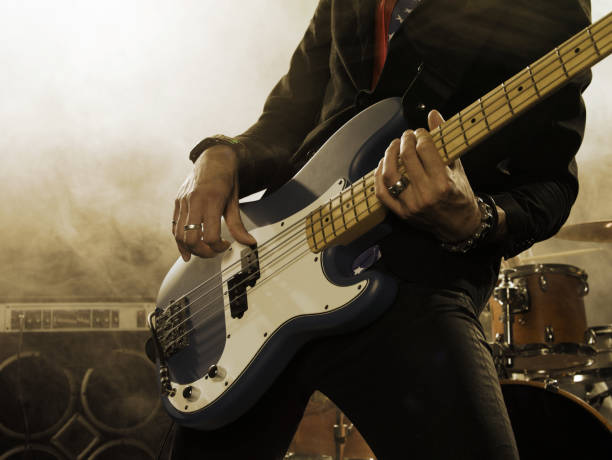 Bassist in the foreground. Rock band performs on stage. Bassist in the foreground. Close-up. bass guitar stock pictures, royalty-free photos & images