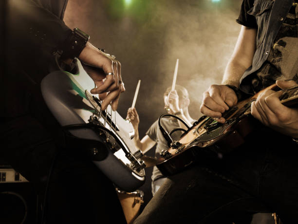 Rock band performs on stage. Guitarist. Rock band performs on stage. Bassist in the foreground. Close-up. modern rock stock pictures, royalty-free photos & images