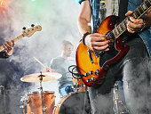 Rock band performs on stage. Guitarist, bass guitar and drums.