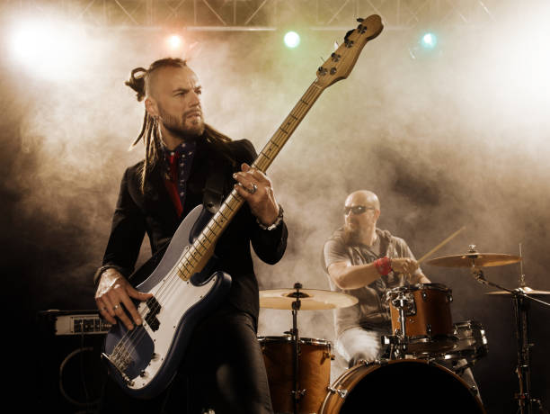 banda de rock se realiza en el escenario. bajista en el primer plano. - rock bass fotografías e imágenes de stock