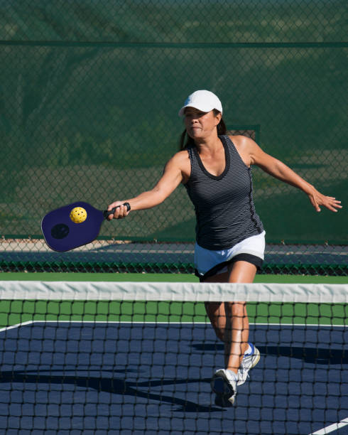Pickleball - Female Player Hitting Forehand Shot Colorful action image of a female pickleball player hitting a forehand shot pickleball stock pictures, royalty-free photos & images