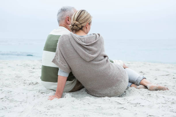 istock Cute couple sitting in the sand 666111358