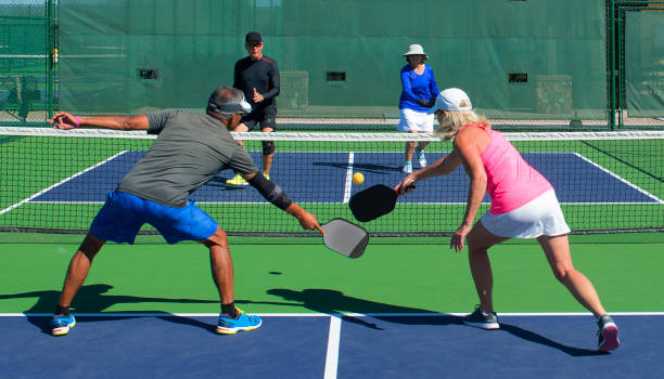 Pickeball - Mixed Doubles Play colorful action image of two couples playing pickleball in a mixed doubles match pickleball stock pictures, royalty-free photos & images