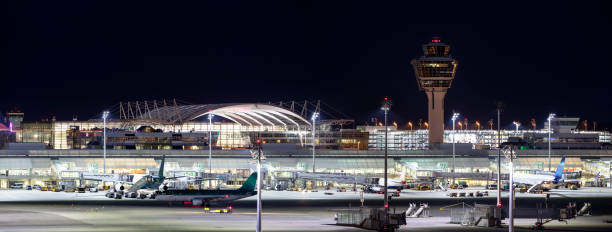 View of Parked Airplanes at Gates, Munich Airport at Night, Germany Franz-Josef-Strauss Munich airport with control tower, four passenger airplanes standing at the gates, apron area, long exposure with tripod, horizontally stitched composition.

 munich airport stock pictures, royalty-free photos & images