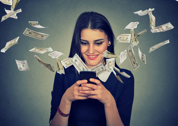 istock Happy young woman using smartphone with dollar bills 666122324