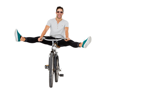 Young man in sunglasses cycling on white background