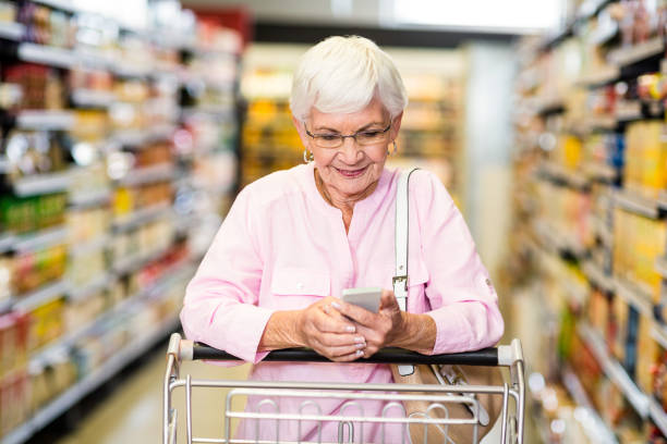 istock Senior woman using phone while pushing cart 666129412