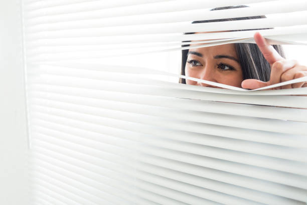 istock Woman peeking through some window blinds 666132074