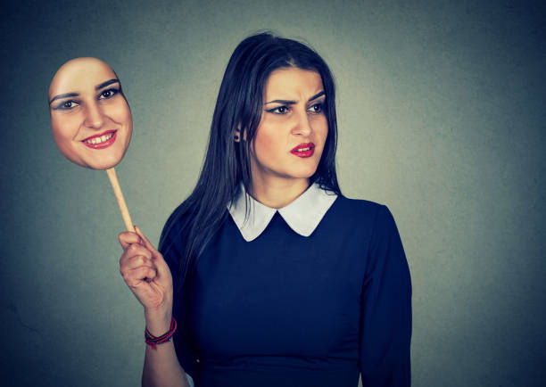 istock Young woman with disgusted sad expression holding a mask expressing cheerfulness 666137426