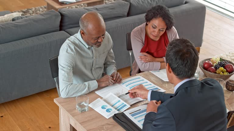 Multi ethnic couple talking to an Asian personal banker at their home