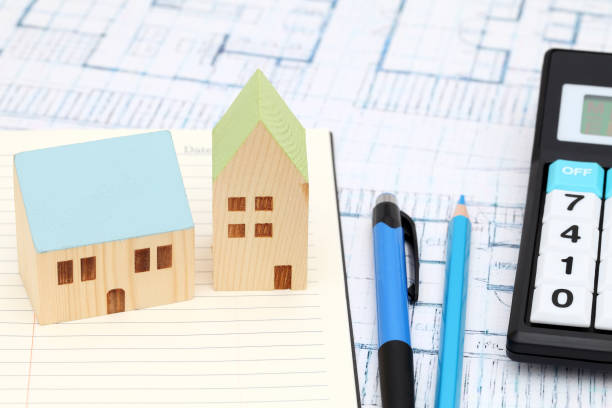 istock Wooden model of house on blueprints 666159626