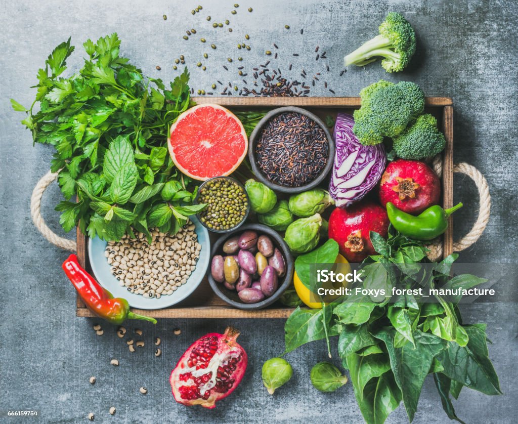 Healthy food ingredients in wooden box over grey background Vegetables, fruit, seeds, cereals, beans, spices, superfoods, herbs, condiment in wooden box for vegan, gluten free, allergy-friendly, clean eating or raw diet. Grey concrete background and top view Antioxidant Stock Photo