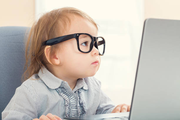 Smart little toddler girl with big glasses on her laptop Smart little toddler girl wearing big glasses while using her laptop nerd kid stock pictures, royalty-free photos & images