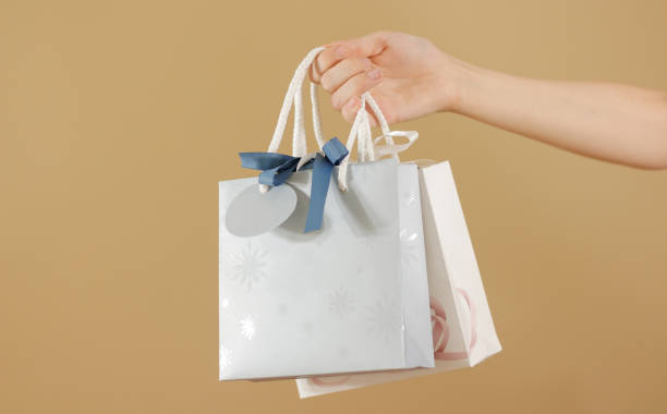 istock Blank two paper gift bag with hearts mock up holding in hand. Empty plastic package mockup hold in hands isolated. Consumer pack ready for logo design or identity presentation. Product packet handle 666184196