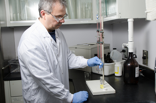 Laboratory worker filling tube glass with medical liquid using pipette\n