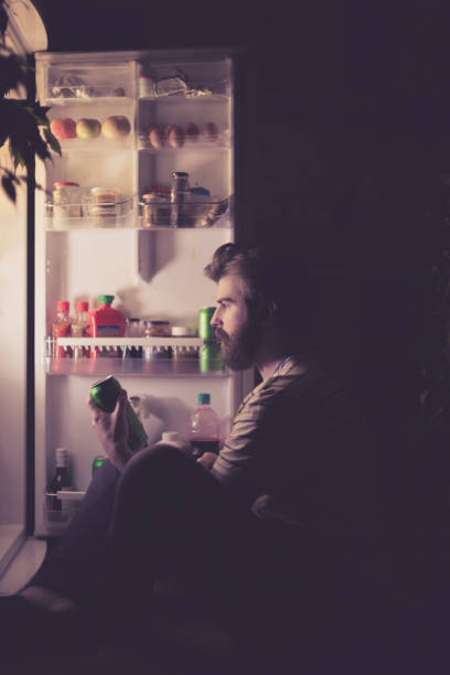 istock Man drinking beer late night in front of the refrigerator 666188138