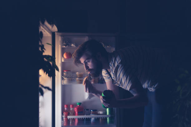 Man having snack and drinking beer late night in front of the refrigerator Man having snack and drinking beer late night in front of the refrigerator midnight stock pictures, royalty-free photos & images