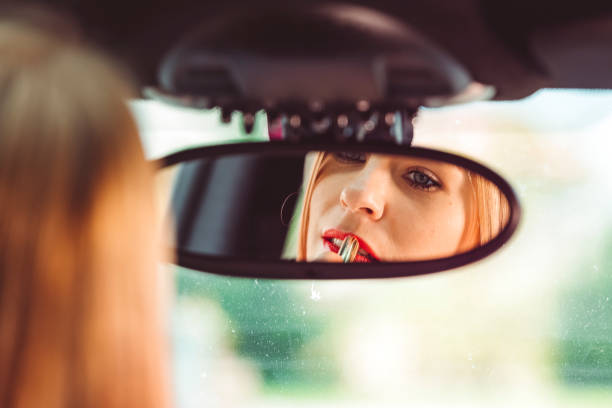 istock Beautiful woman applying makeup in the car 666197088