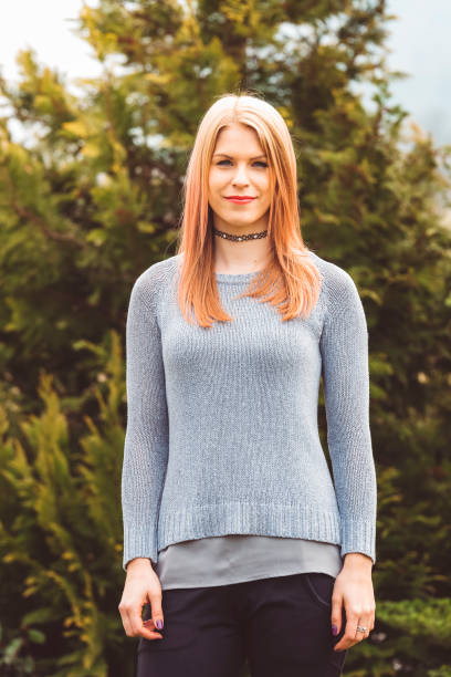 istock Blond woman smiling outdoors with trees in background 666199356