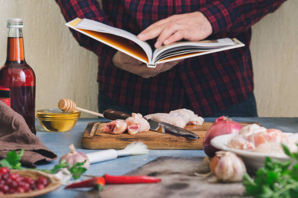 adam kızılcık soslu tavuk kanadı hazırlar - yemek kitapları stok fotoğraflar ve resimler