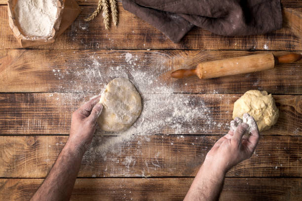 istock Man prepares the dough for cooking pizza on wooden table 666208330