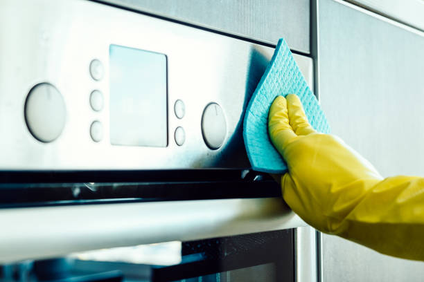 istock Man's hand in yellow glove cleaning the kitchen oven with rag 666211266