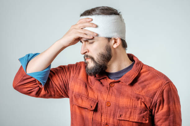 Portrait of man with bandages wrapped around his head isolated on gray background Portrait of man with bandages wrapped around his head isolated on gray background concussion stock pictures, royalty-free photos & images