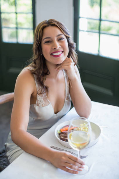 istock Woman smiling while holding wine glass in the restaurant 666220042