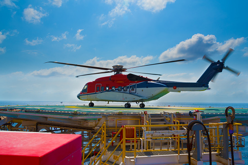 a helicopter landed on offshore drilling rig with blue sky in background