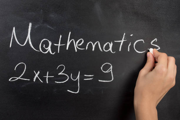 istock Closeup of hand writing complicated math equation on black board. 666239246