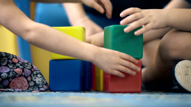Close-up of child's hands playing with colorful plastic bricks