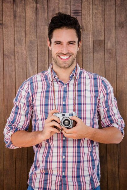 istock Portrait of young man standing with a digital camera 666245606