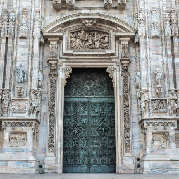 Duomo of Milan, Italy. Detail of facade and main entrance door to the famous cathedral of Milan in Duomo Square. Close up of the entrance of one of the largest Catholic churches in the world (Saint Mary Nascent - Santa Maria Nascente), symbol of the metropolis of Milan, located in the center of Milan in Piazza Duomo candoglia marble stock pictures, royalty-free photos & images