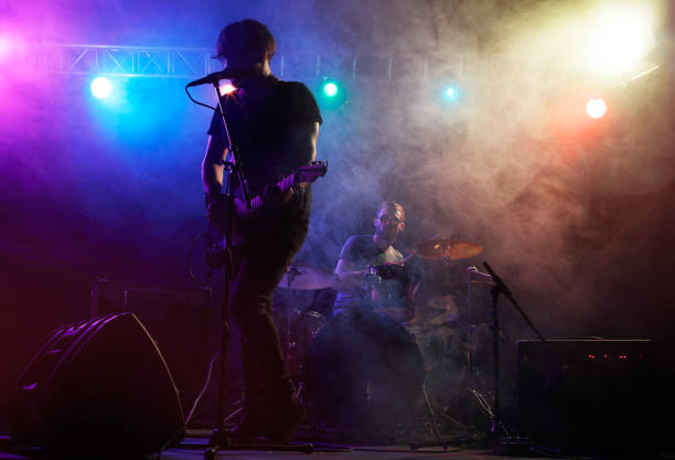 Close up of unrecognizable rock musician playing electric guitar in smoke with focus on hands copy space