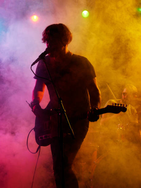 Silhouette of guitar player on stage. Silhouette of guitar player on stage. Dark background, smoke, spotlights pop music stock pictures, royalty-free photos & images