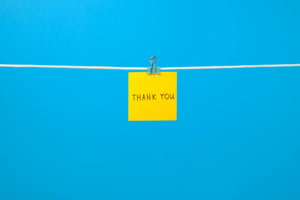 Yellow paper note on clothesline with text Thank You over colorful background
