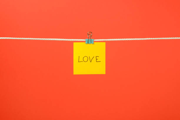 istock Yellow paper note on clothesline with text Love over colorful background 666265676