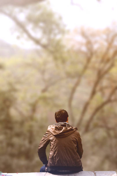 istock Rear view of alone young male sitting in solitude 666271836