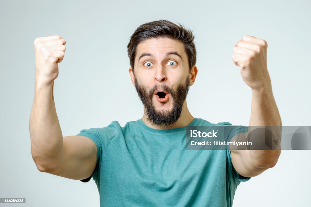 Young man and sign of victory isolated on gray background Winning Stock Photo