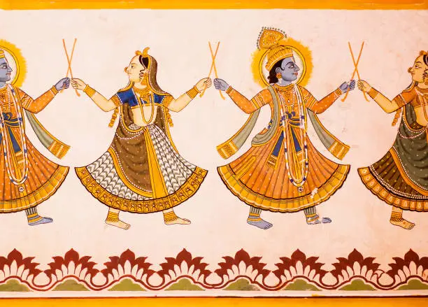 Photo of Hindu gods dancing on a fresco with colorful paints on carved wall of 19th century house in India.