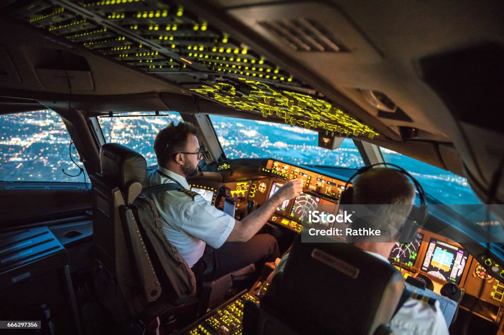 Flightdeck View Two pilots at work during departure of Dallas Fort Worth Airport in United States of America. The view from the flight deck with high workload the beginning night through the wind shield Pilot Stock Photo