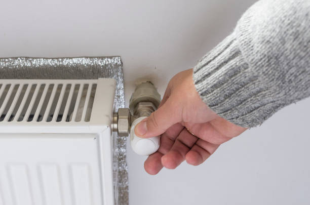 istock Person adjusting thermostat control on a central heating. 666311454