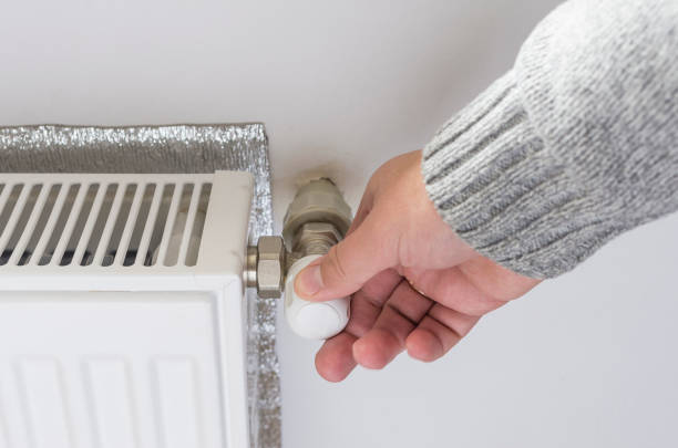 istock Person adjusting thermostat control on a central heating. 666311492