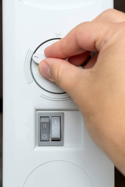 istock Person adjusting thermostat control on a electric heater. 666314248