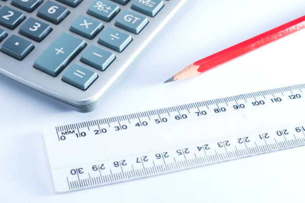 A calculator, lead pencil and ruler arranged together on a white background